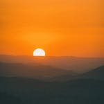 A beautiful sunset casting warm hues over a mountainous landscape.