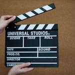Close-up of Universal Studios clapboard on a cork background held by hands.