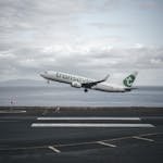 Transavia airplane taking off from a runway with ocean view.